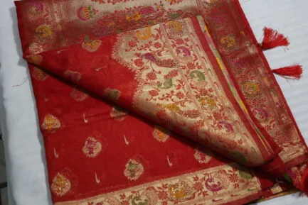 Close-up view of a red and gold ornate Indian saree, showcasing its detailed embroidery.