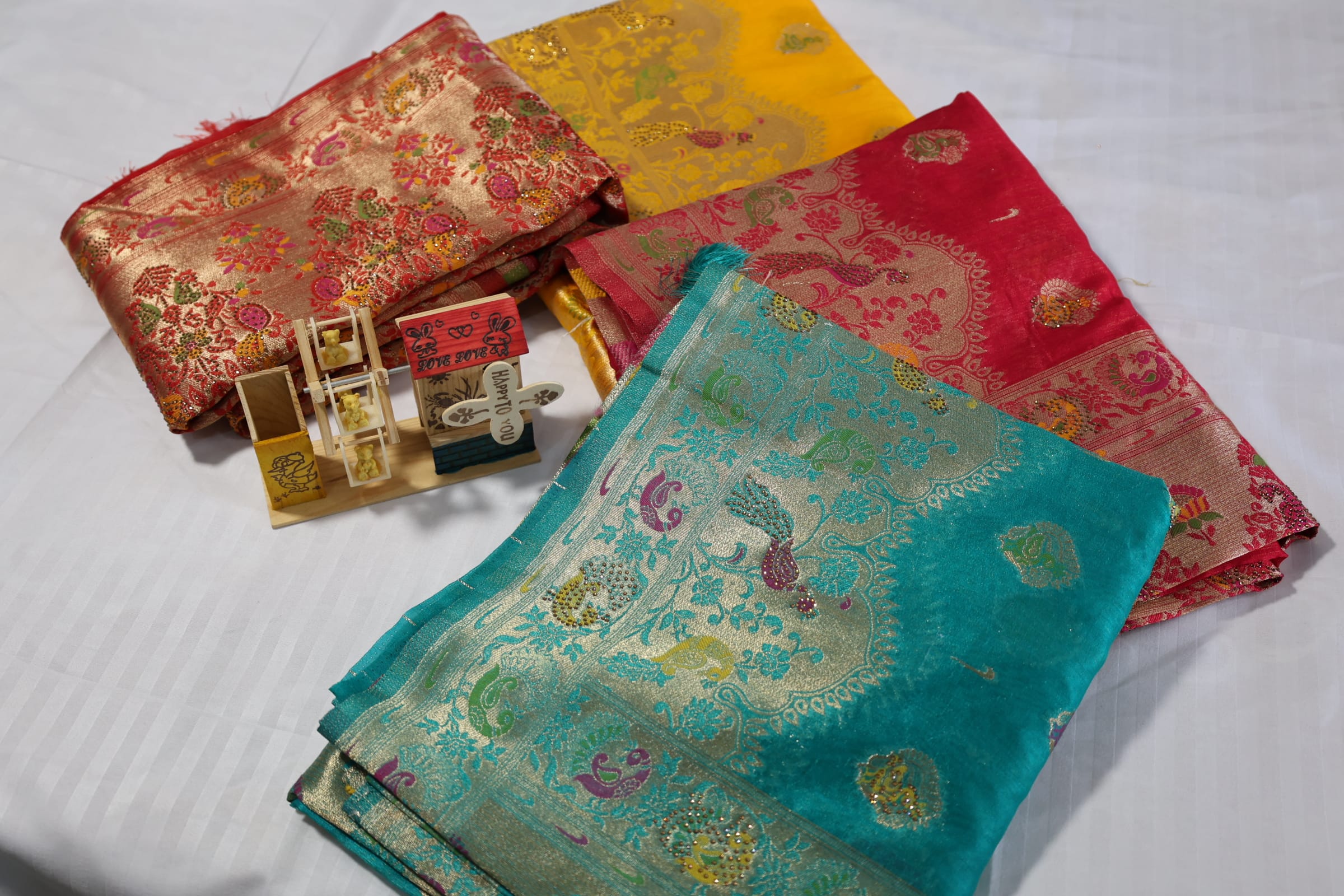 A group of beautifully patterned Indian sarees folded and displayed on a surface