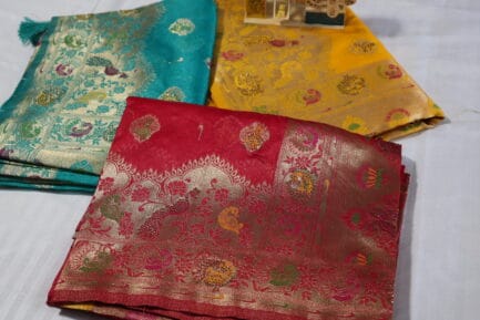 Bnarasi Pure Silk Golden Zari Saree A group of beautifully patterned Indian sarees folded and displayed on a surface