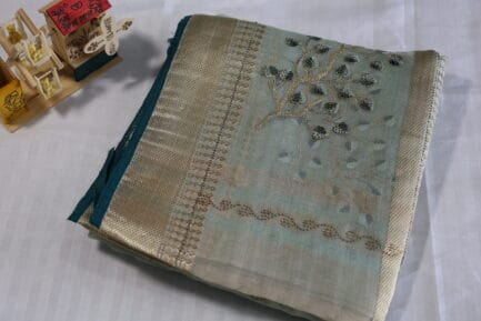 grey green-colored silk saree with a golden border and embroidered flowers.